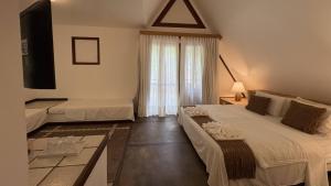 a hotel room with two beds and a television at Hotel Pousada Pitinga in Arraial d'Ajuda