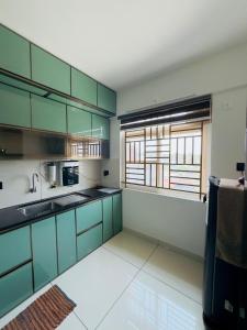 a kitchen with green and white cabinets and a window at Haven by Glass Loft-Premium 2BHK near KIMS and GG Hospital in Trivandrum
