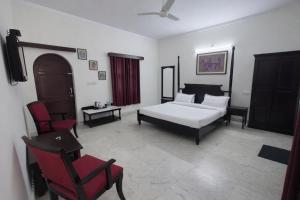 a bedroom with a white bed and a red chair at Hotel Gajender Niwas Sun City A Boutique Stay in Jodhpur