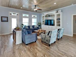 a living room with a couch and chairs and a tv at Postcard from Paradise in Padre Island