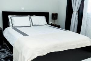 a bedroom with a large bed with white sheets and pillows at Saton 24H Guest House in São Tomé +17 photos