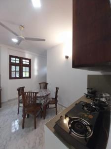 a kitchen with a stove and a table with chairs at Villa Anu in Hikkaduwa