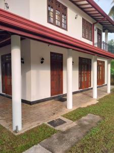 a house with columns and doors and a yard at Villa Anu in Hikkaduwa
