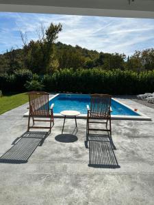 two chairs and a table next to a swimming pool at Holiday House Maya in Mostar