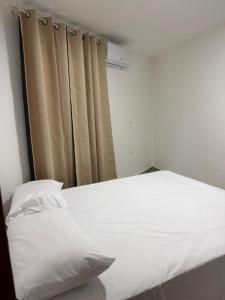 a bedroom with a white bed and a curtain at Brisas del mar in Santa Cruz de Barahona