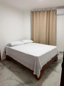a bedroom with a bed with a white blanket on it at Brisas del mar in Santa Cruz de Barahona