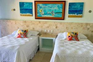 two beds in a room with paintings on the wall at Villa Arkoi in Uaymitun
