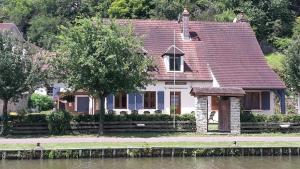 a house with a red roof next to a river at Le petit Flotteur in Chevroches +4 photos