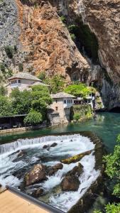 a river with a house on the side of a mountain at Holiday House Maya in Mostar