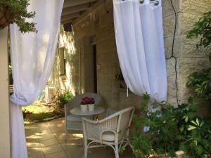 a patio with a table and chairs and white curtains at נופש בפינה in Rosh Pinna