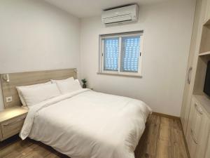 a bedroom with a large white bed and a window at Casa Luca in Carvoeiro