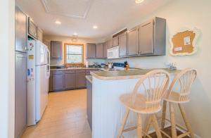 a kitchen with blue cabinets and two stools at a counter at Beach Place - Corolla, Ocean Sands, 370 Yards to the Beach, Flex Stays, Pets OK, Pool! in Corolla