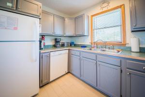 a kitchen with blue cabinets and a white refrigerator at Beach Place - Corolla, Ocean Sands, 370 Yards to the Beach, Flex Stays, Pets OK, Pool! in Corolla