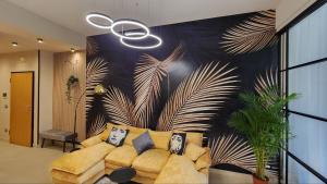 a living room with a couch and a wall with palm leaves at Park & Seafront Pescara in Montesilvano