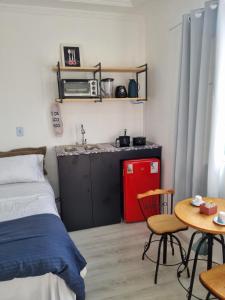 a bedroom with a bed and a table and a kitchen at Suíte Garden em Butantã Próximo á USP - Self Check-in in São Paulo