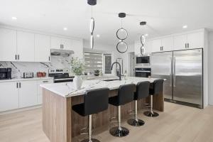a kitchen with a kitchen island with black bar stools at Executive Acreage 3 King Beds Fireplace AC in Airdrie