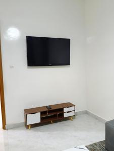 a living room with a tv on a white wall at GALSEN LODGe in Thiès
