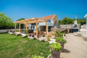 a backyard with a pergola and benches and flowers at Holiday house with heated pool in Neorić