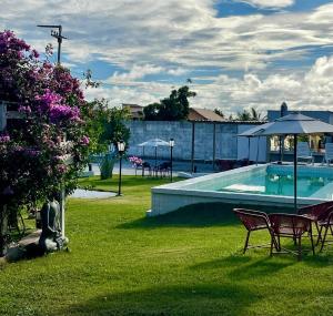 ein Swimmingpool im Garten mit Stühlen und Sonnenschirmen in der Unterkunft Pousada Mali in Canoa Quebrada