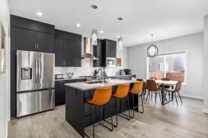 a kitchen with black cabinets and a kitchen island with orange chairs at Arcade King Bed Espresso Maker Family Friendly in Airdrie