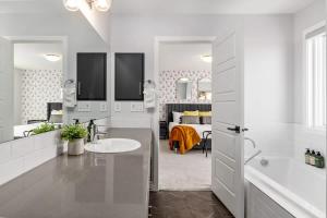 a white bathroom with a sink and a bedroom at Arcade King Bed Espresso Maker Family Friendly in Airdrie +6 photos