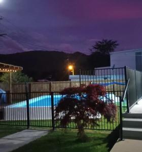 a fence in front of a swimming pool at night at B&B on Station in Paeroa