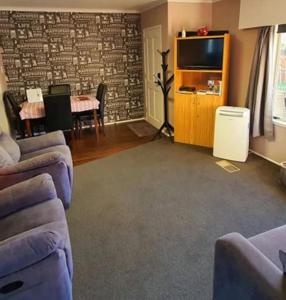a living room with two couches and a tv at B&B on Station in Paeroa