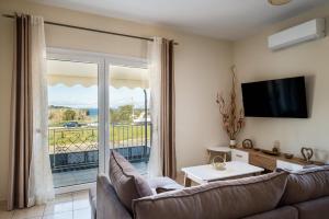 a living room with a couch and a tv and a balcony at Ioana Sea View in Corfu