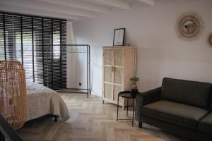 a bedroom with a bed and a couch and a chair at Loft 15 in Alkmaar