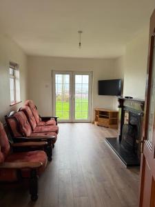 a living room with couches and a fireplace and a television at Beachfront Cottage - 3 bedrooms in Clogherhead