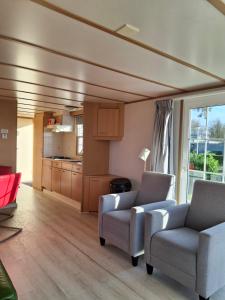 a living room with two chairs and a kitchen at 17e straatje in Elburg