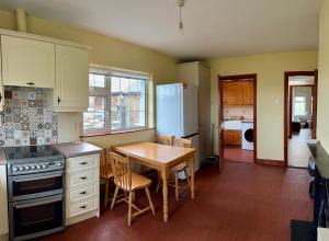 a kitchen with a table and a refrigerator and a table and chairs at Beachfront Cottage - 3 bedrooms in Clogherhead