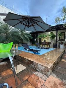 a patio with an umbrella and chairs and a pool at Excelente Casa para 10 pessoas proximo ao Shopping Flamboyant- Serra Dourada-Autódromo in Goiânia