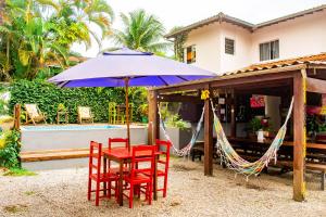 a table and chairs with a hammock and an umbrella at Che Lagarto Paraty in Paraty