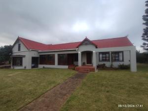 a white house with a red roof and a yard at Forest Hill Accomodation in Port Alfred