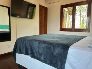 a bedroom with a large bed with a window at Micas House in Ilhabela