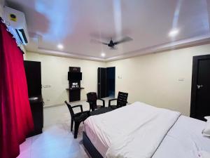 a bedroom with a bed and a table and chairs at The Royal Comforts in Visakhapatnam