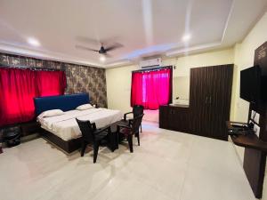 a bedroom with a bed with red curtains and a television at The Royal Comforts in Visakhapatnam