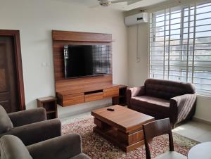 a living room with a tv and two chairs and a table at Chateau de Mankosah in Accra