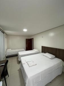 ein Hotelzimmer mit zwei Betten, einem Tisch und Stühlen in der Unterkunft Seller Hotel in Sobral + 102 Fotos