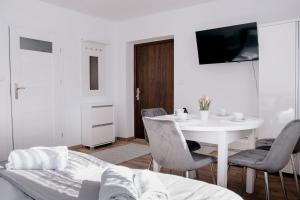 a white room with a table and chairs and a tv at Apartamenty Pienińska Aura in Czorsztyn