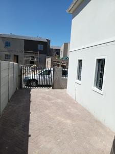 a white building with a gate and a brick driveway at Coastal Guest House with Free Parking and Braai Area in Cape Town