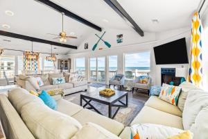 a living room with couches and a flat screen tv at Beachfront Villa Royale OBX in Avon