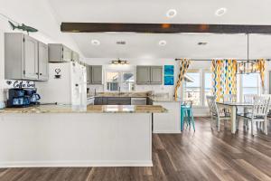 a kitchen with white cabinets and a table with chairs at Beachfront Villa Royale OBX in Avon
