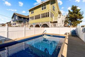 a house with a swimming pool in front of a house at Beachfront Villa Royale OBX in Avon