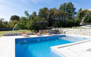 a swimming pool with two chairs and an umbrella at Old Oak Villa-house with Private Pool, Authentic Tavern & BBQ in Hrvace