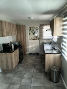 a kitchen with wooden cabinets and a white door at Coastal Guest House with Free Parking and Braai Area in Cape Town
