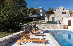 a pool with two lounge chairs and an umbrella at Old Oak Villa-house with Private Pool, Authentic Tavern & BBQ in Hrvace