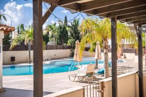 a swimming pool with two chairs and umbrellas at Elia House In Kapparis in Paralimni