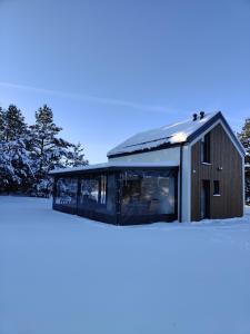 a house with a glass facade in the snow at Domek Sarnia in Podmacharce
